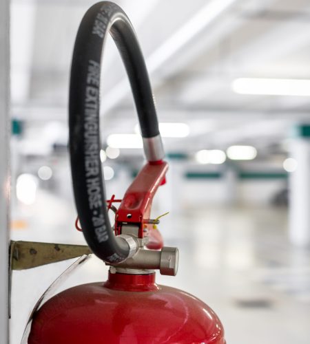 Extreme close-up of a fire extinguisher placed on the column of a car park